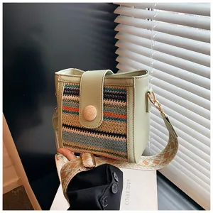 Detail shot of the stylish green women bucket bag with woven pattern and wide shoulder strap.
