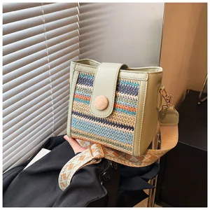 Detail close-up of stylish woven bucket bag featuring green leather trim and colorful patterns.