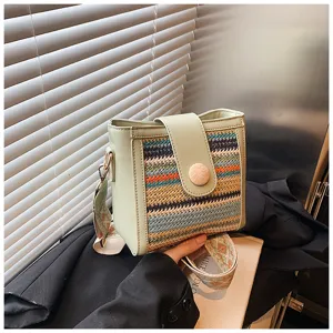 Detailed view of the woven bucket bag with wide strap and unique patterned design.