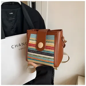 Woven bucket bag detail view, brown leather trim, colorful pattern and wide strap.