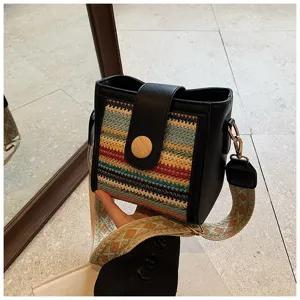 Close-up detail of stylish woven bucket bag with black PU trim and wide ethnic pattern strap.