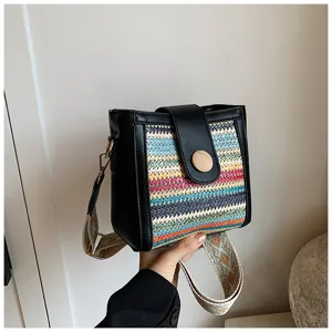 Detail view of woven bucket bag, colorful pattern panel, wide strap and wooden button closure.