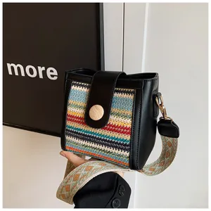 Detailed view of the stylish woven bucket bag with black leather trim and wide shoulder strap.