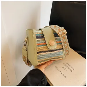 Chic woven bucket crossbody bag featuring light green leather trim and a stylish wide strap.