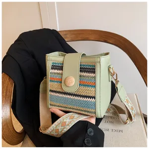 Detailed view of the stylish woven bucket bag with wide strap and wooden button design.
