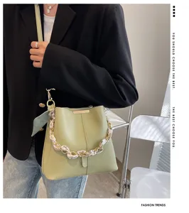 Detailansicht der stylischen hellgrünen Beuteltasche mit chicem Ketten- und Seidenschal-Riemen.