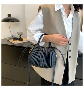 Detailansicht einer modischen schwarzen Plissee-Beuteltasche mit Kordelzug und Riemen.