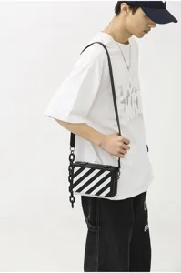 Sac bandoulière tendance style boîte unisexe avec rayures diagonales et chaîne audacieuse.