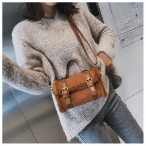 Details of the brown plush suede crossbody bag with double buckle straps in a chic outfit scene.