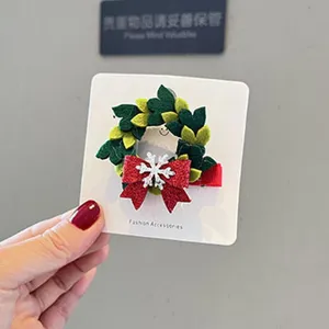 Nahaufnahme der Weihnachtshaarspange mit grünem Kranz und roter Glitzerschleife für Feiertage.