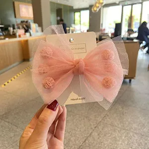 Vista dettagliata di un grazioso fermaglio per capelli con fiocco in rete rosa per le bambine.
