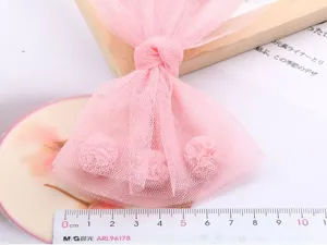 Vista dettagliata della molletta per capelli con fiocco in tulle rosa, glitter e fiori.
