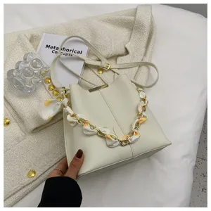 Nahaufnahme der eleganten weißen Beuteltasche mit schicker Kette und Seidenschalriemen.