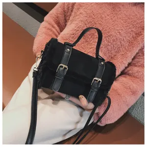 Black fuzzy crossbody handbag detail, plush texture with double buckle straps design.