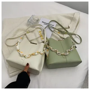 Detailansicht der stylischen Dameneimer Tasche mit Metallkette und Seidenschal, minimalistisch.