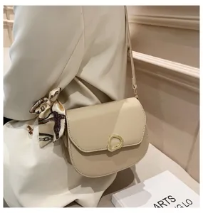Beige Umhängetasche im Sattel-Design mit goldenem Ringverschluss und Seidenschal.
