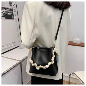 Detailansicht der schwarzen Leder Beuteltasche mit Kette und Seidenschal Akzent.