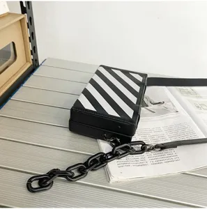 Vue détaillée du sac bandoulière élégant à rayures diagonales noires et blanches avec chaîne.