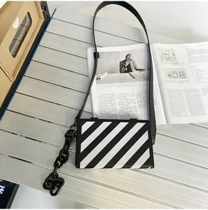 Vue détaillée d'un sac bandoulière boîte rayé diagonal noir et blanc avec une chaîne épaisse.