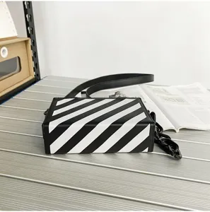 Vue détaillée du sac bandoulière boîte à rayures diagonales noires et blanches.