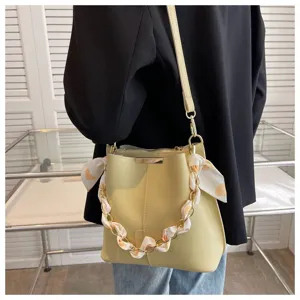 Detailansicht der gelben Beuteltasche mit goldener Kette und elegantem Schal Design.