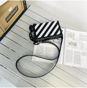 Vue détaillée du sac bandoulière boîte rayé diagonal noir et blanc élégant avec chaîne.