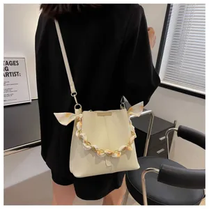 Detailansicht der stilvollen Beuteltasche in Beige mit schicker Kette und Schalgriff.