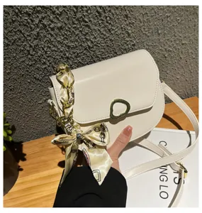 Weiße Satteltasche Detailansicht mit Metallkettengurt und eleganter Seidentuch-Schleife.