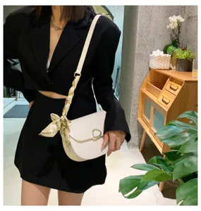 Detailaufnahme einer trendigen weißen Satteltasche mit Schal-Kette und Metallverschluss.