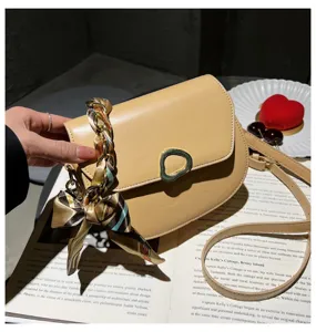 Nahaufnahme der trendigen beigefarbenen Umhängetasche mit Schal-Kette und Metallverschluss.