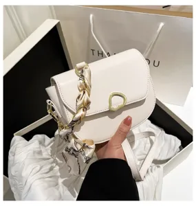Detailansicht der weißen Mode-Satteltasche mit Kette und Seidenschal, stylisches Design.