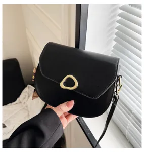 Detailansicht einer eleganten schwarzen Satteltasche mit goldener Schnalle und Seitenschal.