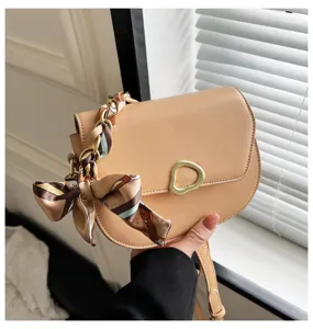 Nahaufnahme der stilvollen Retro-Satteltasche mit Seidenschal und goldener Schnalle.