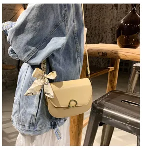 Detailansicht der stilvollen beige Satteltasche mit Schal und Metallverschluss.