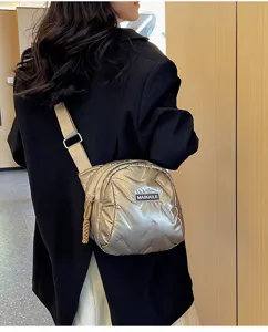 Detailaufnahme einer glänzenden metallischen Stepp Umhängetasche in Innenräumen.