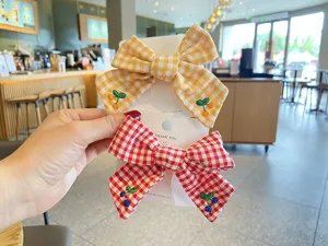 Detailed view of cute plaid bow hair clips with sweet embroidered cherry design for kids.