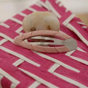 Close-up detail of a pink grosgrain ribbon wrapped BB hair clip, cute children hair accessory.