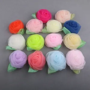 Close-up detail of colorful chiffon rose fabric flowers with green leaves for DIY hair bows.