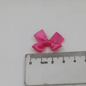 Vue détaillée d'un petit nœud en ruban de satin rose avec une règle pour la taille, DIY.