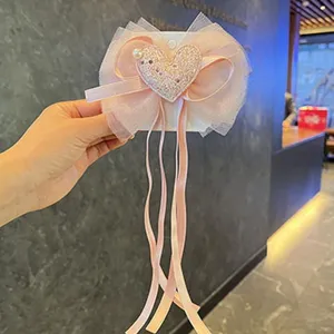 Detail view of the cute children hair clip featuring mesh bow, ribbons, and sparkling heart.