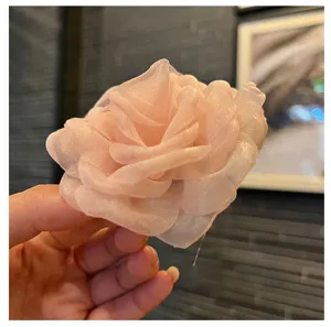 Close-up of handmade pink organza fabric flower detail for DIY hair accessory and garment decoration.