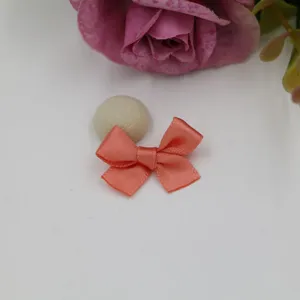 Gros plan d'un délicat nœud en ruban satin rose corail pour accessoire de bricolage DIY.