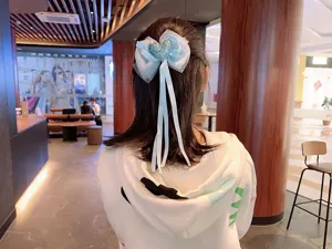 Detailed view of the blue mesh bow hair clip with pearl and heart, worn on hair.