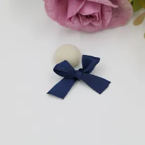Vue détaillée du nœud en ruban bleu foncé fait main et de la boule en tissu beige.