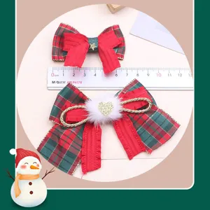 Close-up detail of Christmas red and green plaid hair bow with cute pompom and sparkly heart accent.