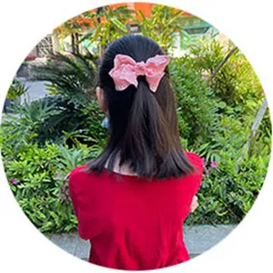 Detail shot of a pink fabric bow hair clip worn on a ponytail, lovely children's hair accessory.