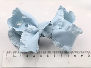 Detailed close-up view of a light blue fabric ruffled bow hair clip, sweet style.