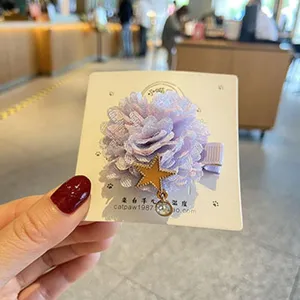 Nahaufnahme eines charmanten lila Spitzenblumen-Haarclips mit Stern-Anhänger für Kinder.