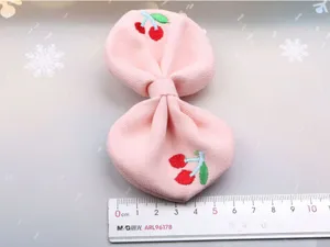 Detailed view of cute pink bow hair clip featuring sweet cherry embroidery, perfect for sweet styles.