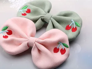 Detail shot of cute children fabric hair clips with embroidered cherry design in pink and green
